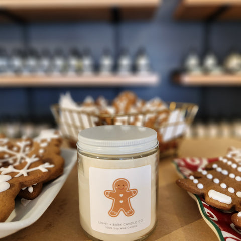 A beautiful candle in a holiday gift box nestled next to a sleeping puppy